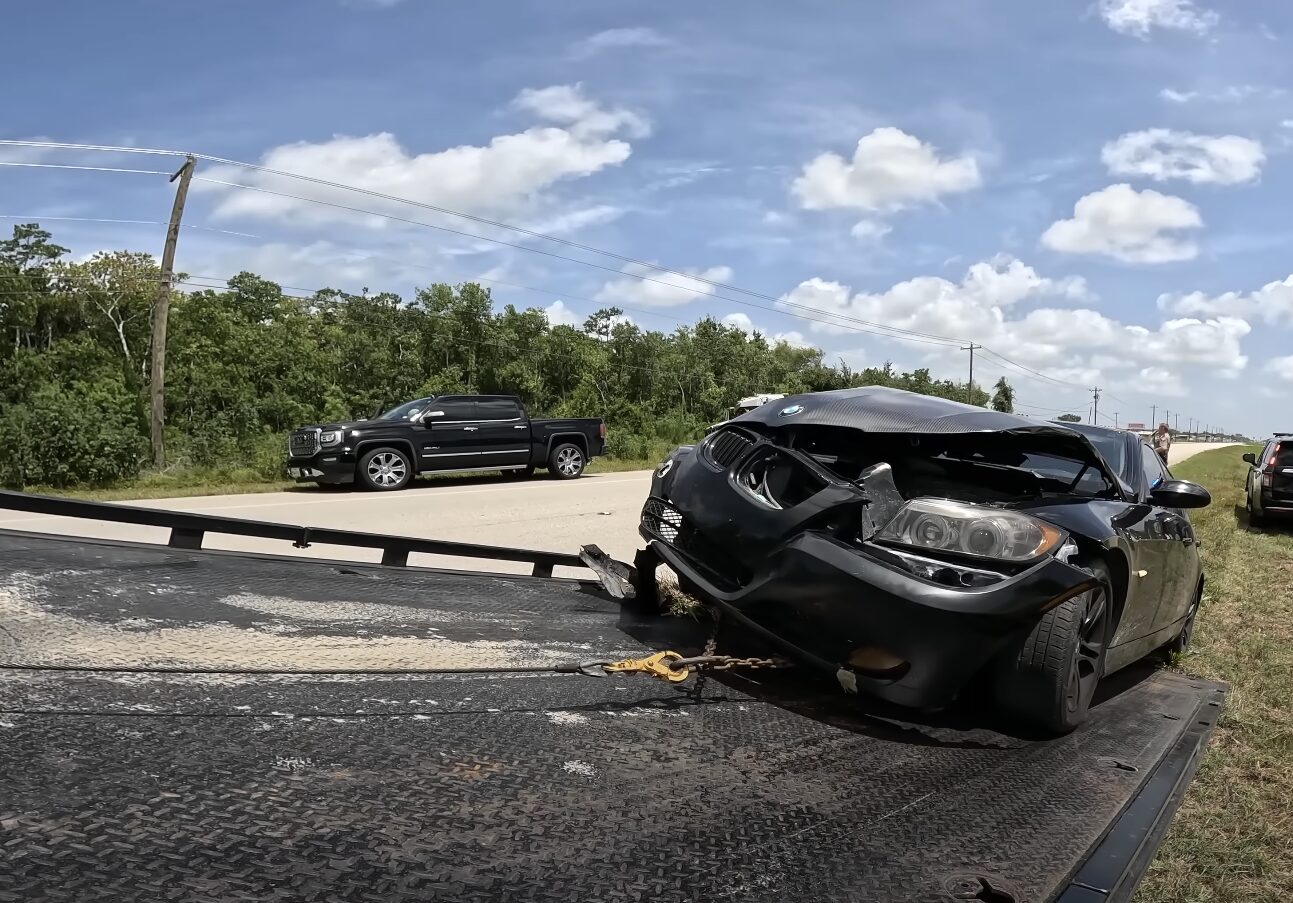 Professional Flatbed Towing - Safe Vehicle Transport Damaged black sedan being recovered after highway accident